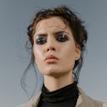 Stunning portrait of a model with bold eyeshadow and styled hair against a clear sky backdrop.